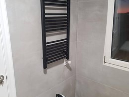 Detalle de radiador toallero negro en baño